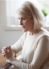 image of woman seated at a table with her hands together